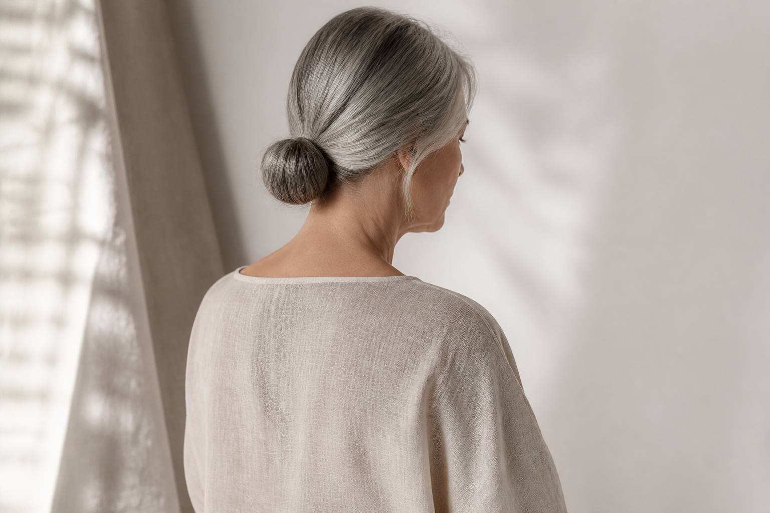 Femme élégante vue de dos avec des cheveux gris argentés en chignon bas